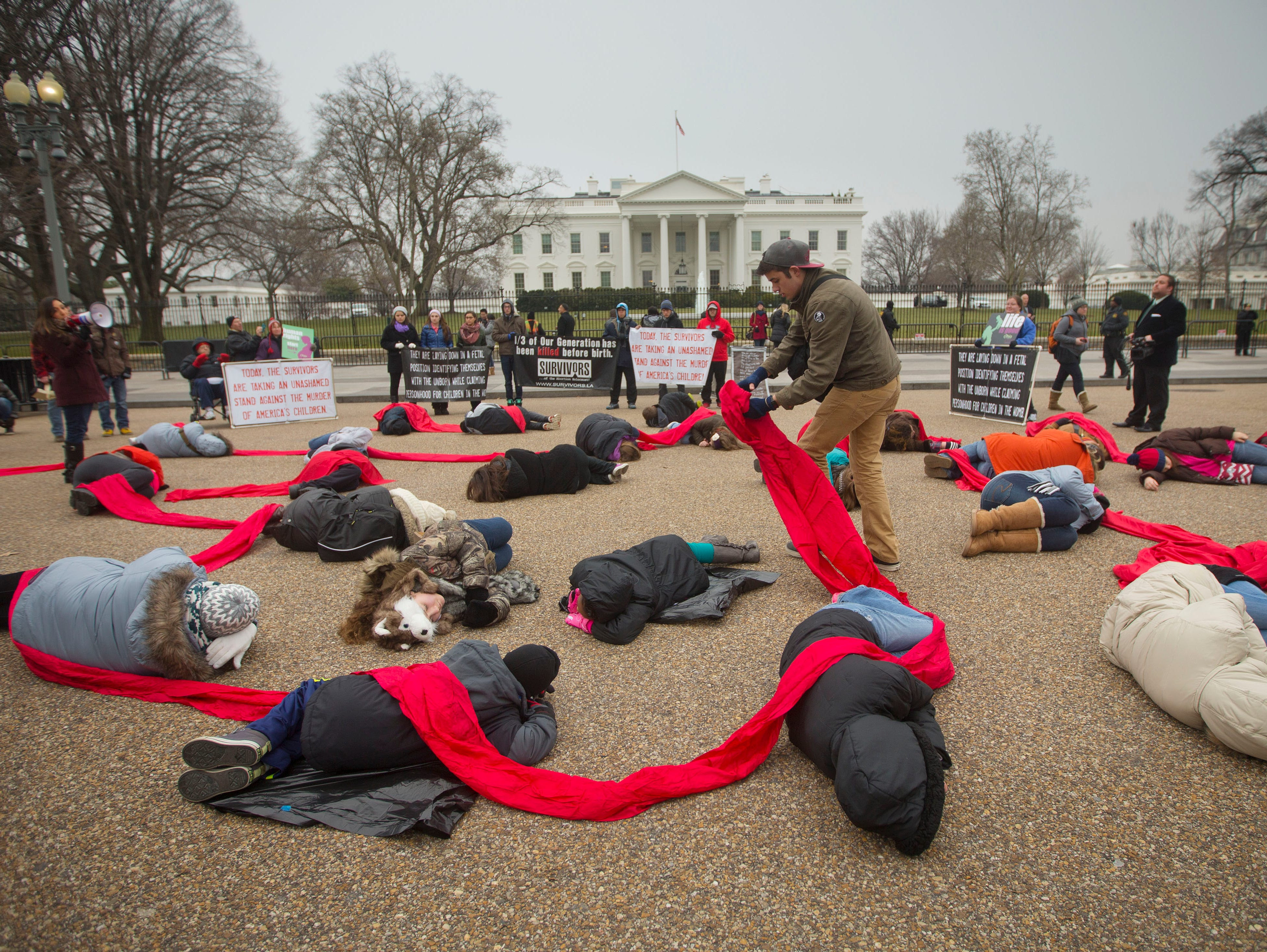 Abortion rights opponents are connected with a red piece of cloth as they stage a 'die-in' in front of the White House in Washington, Wednesday.
