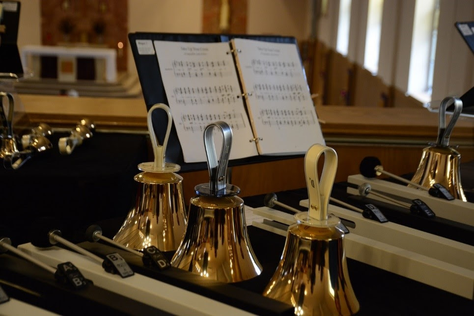 Photo of three golden bells and some sheet music.