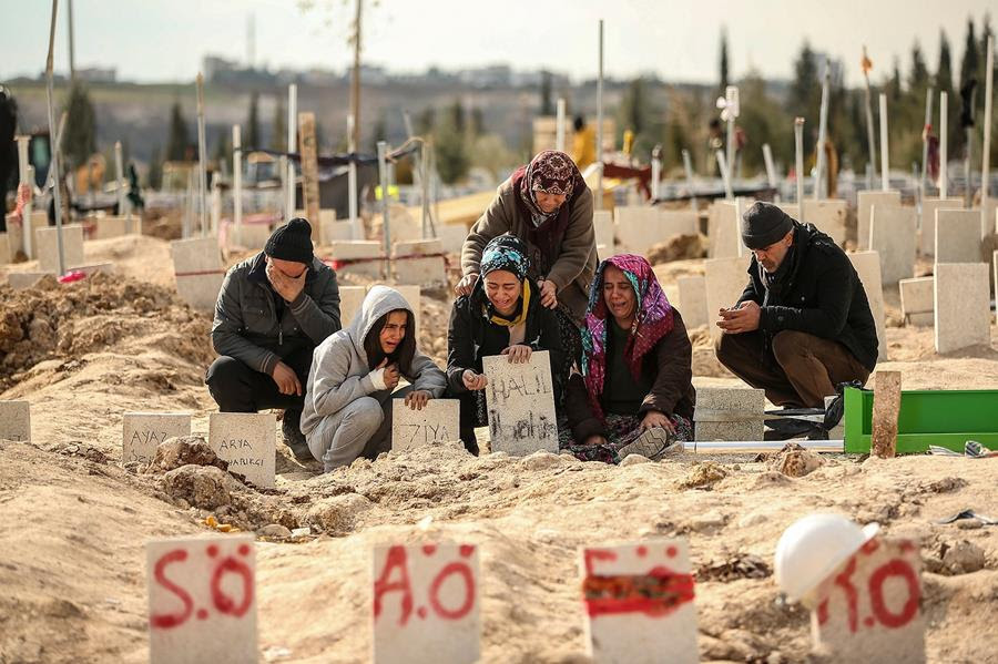 A group of mourners weeps at a mass grave site.