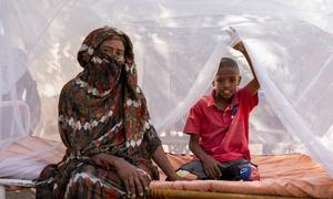 Una madre y su hijo sentados en una cama con mosquiteros tratados con insecticidas de larga duración distribuidos por UNICEF y sus socios en el estado de Kassala, Sudán.