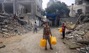 Niños buscando agua en un barrio bombardeado en Gaza.