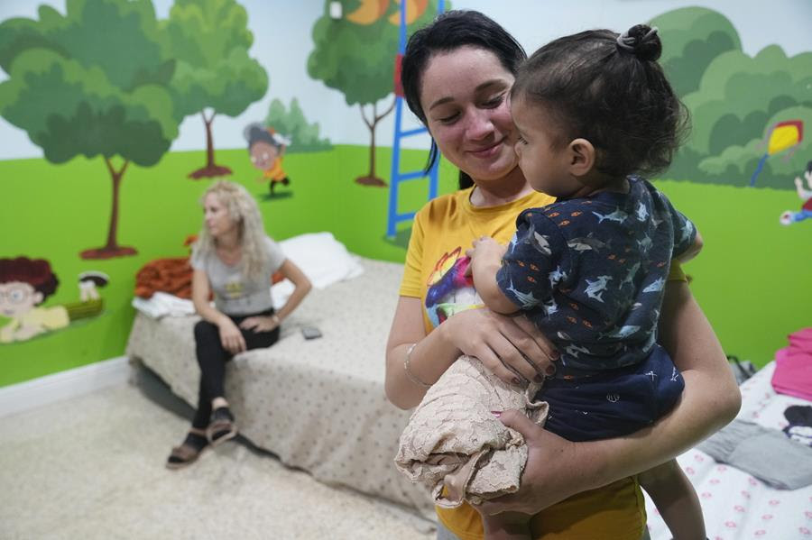 Isabel Bembow Tamayo holds Liam Centeno, 1, in the Iglesia Rescate school classroom that is converted into a bedroom for her family, Tuesday, Feb. 21, 2023, in Hialeah, Florida.