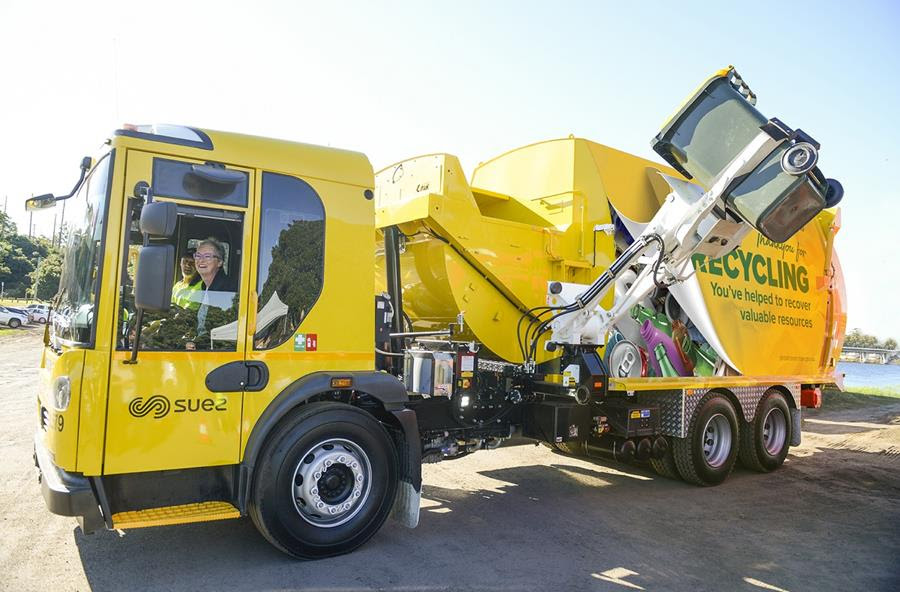 Photo of Mayor Amanda Findley in a new yellow garbage truck smiling out the window.