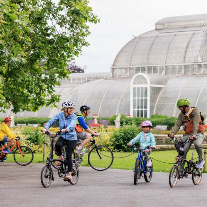 A group of people cycling in front of the Palm House