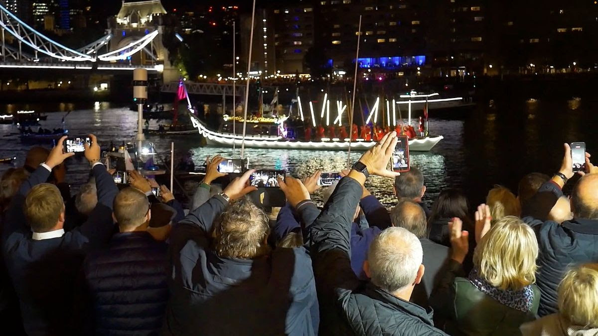 People taking pictures of a boat at night on their phones