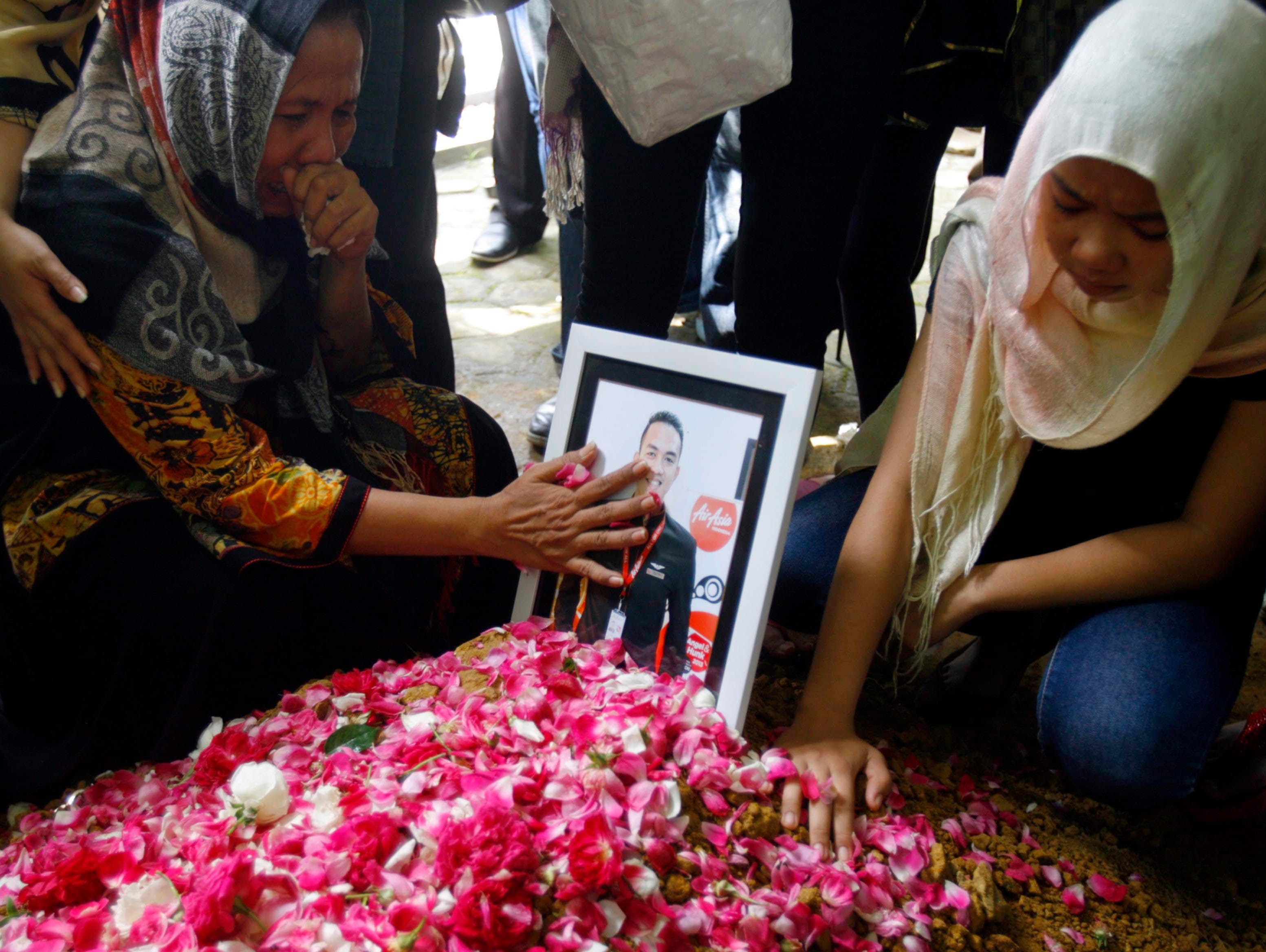 Relatives of Oscar Desano, one of the cabin crew of crashed AirAsia flight QZ8501, mourn during his burial at a cemetery in Klaten, Central Java province, Indonesia.