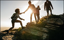 The figure shows a group of young people on a mountain hike at sunset.