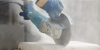 Close-up of a saw cutting into stone, creating dust.