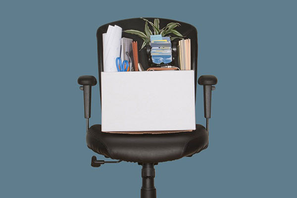 Una silla de oficina negra con una caja de cartón llena de archivos, material de oficina y una maceta en equilibrio sobre el asiento