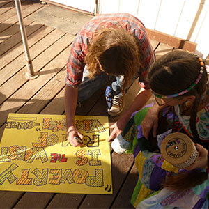 two adults coloring on poster