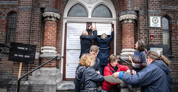 Nijmeegse lutheranen spijkeren stellingen op de kerkdeur, uit protest tegen verkoop