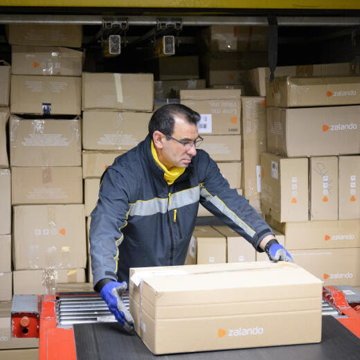 Un employe de la poste suisse charge des paquets "Zalando" dans un container au centre colis de La Poste ce jeudi 15 decembre 2022 a Daillens, Vaud. Pendant les jours de pointe avant Noel, le volume depasse souvent les 230 000 colis. La capacite de tri maximale s'eleve a 19 000 colis par heure. En 2021, la Poste a trie au total 45,2 millions de colis a Daillens. (KEYSTONE/Laurent Gillieron)