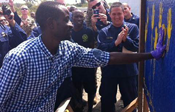 U.S. Public Health Service officers celebrate as a Liberian man adds his handprint to a “survivors’ wall.” Each patient who overcame Ebola after treat