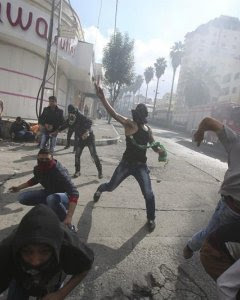 Manifestantes palestinos lanzan piedras contra soldados israelíes durante enfrentamientos en la ciudad cisjordana de Hebrón. EFE/ABED AL HASHLAMOUN