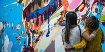 Two women look at a mural with their arms around each other