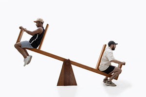 Visitors playing with a wooden sculpture that works as a seesaw