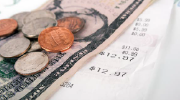 A five-dollar bill and spare change sit on top of a restaurant receipt.