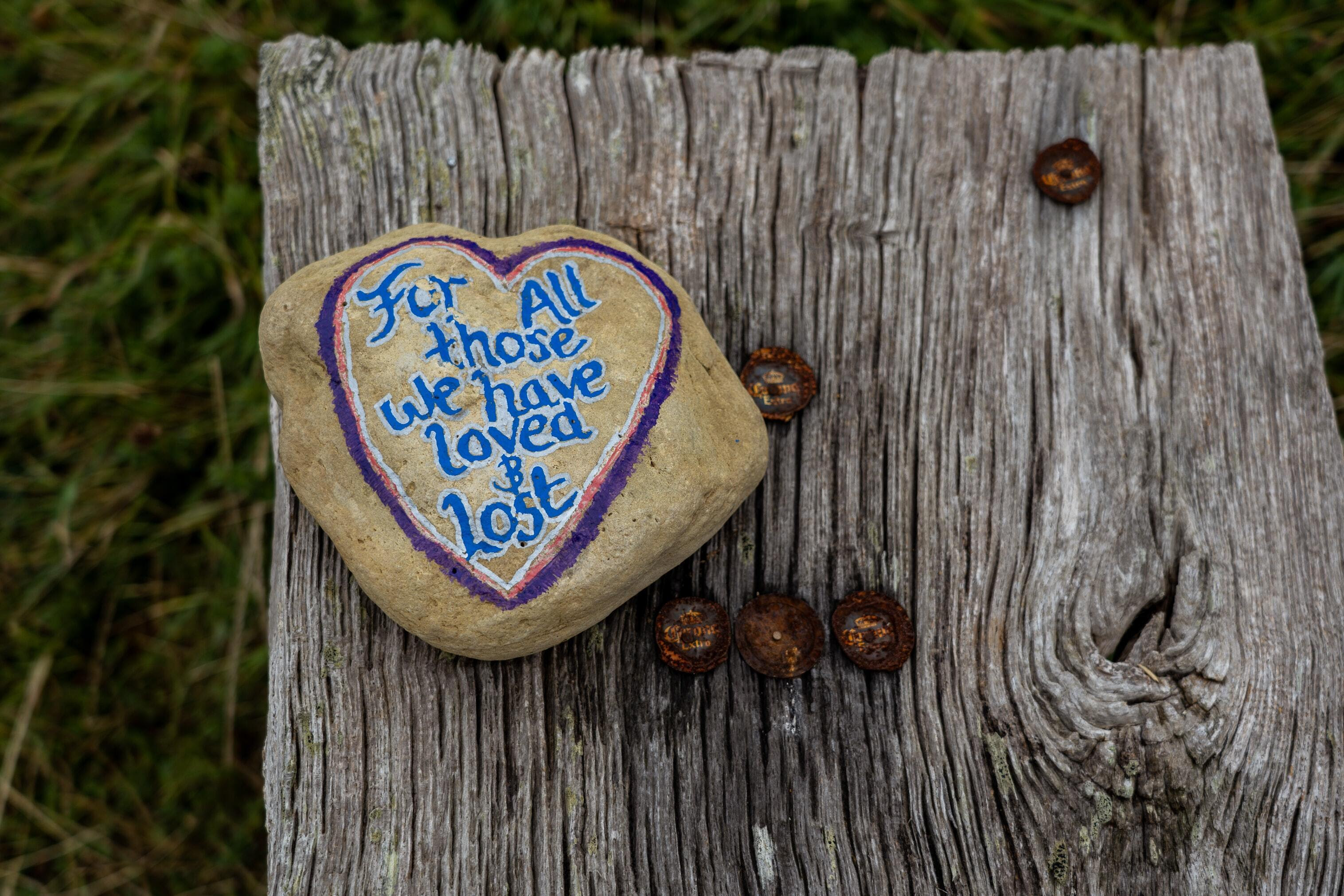 A rock painted with the words "For all those we have loved and lost"