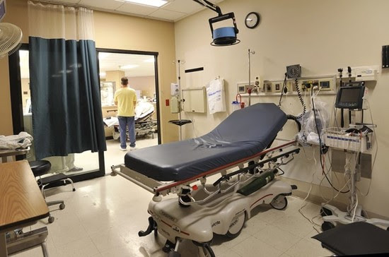 A photo of an empty hospital bed surrounded by health care equipment.