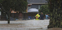 Emergency workers and a man wade through flood waters in Auckland, New Zealand, Friday, Jan. 27, 2023. Torrential rain and wild weather in Auckland causes disruptions throughout the city and an Elton John concert to be canceled just before it was due to start. (Hayden Woodward/New Zealand Herald via AP)/XNZH803/23027312025390-0/NEW ZEALAND OUT, NO SALES, AP PROVIDES ACCESS TO THIS THIRD PARTY PHOTO SOLELY TO ILLUSTRATE NEWS REPORTING OR COMMENTARY ON FACTS DEPICTED IN IMAGE; MUST BE USED WITHIN 14 DAYS FROM TRANSMISSION; NO ARCHIVING; NO LICENSING; MANDATORY CREDIT/2301270952