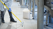 A worker cleans the floor of a food processing plant.