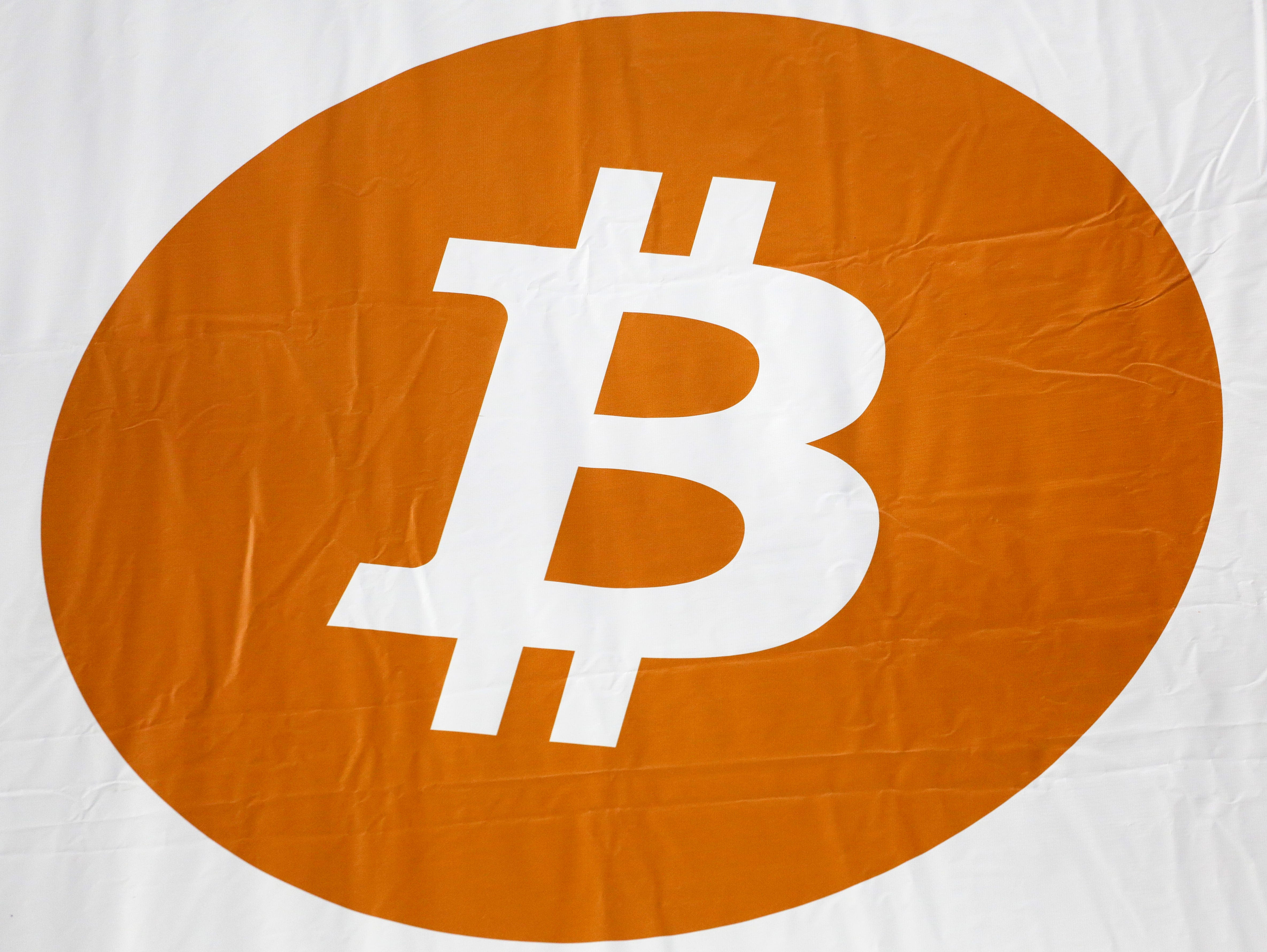 A bitcoin logo is displayed at the Inside Bitcoins conference and trade show, Monday, April 7, 2014 in New York. Bitcoin users exchange cash for digital money using online exchanges, then store it in a computer program that serves as a wallet. The pr