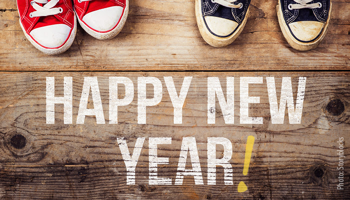Happy New Year! written on wood floor with two sets of sneakers in red and blue