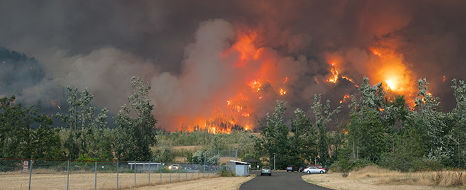 wildfires burning behind a facility in the foreground