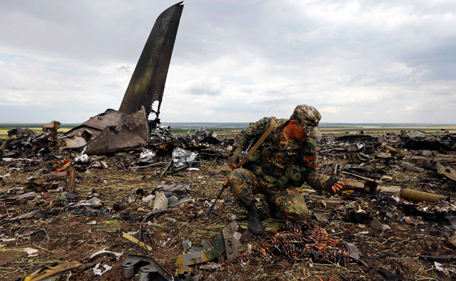 Un rebelde prorruso recoge munición del avión del Ejército derribado por las milicias en Lugansk con 49 militares a bordo.