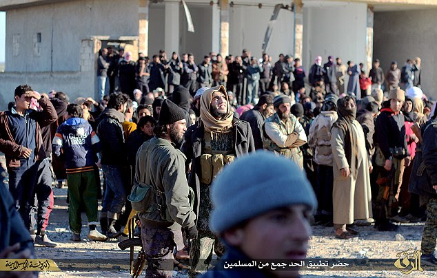 Bearing witness: A large crowd of fighters and local residents of Raqqa is shown gathering to watch the horrific punishment outside the Islamic court building in Tal Abiad.