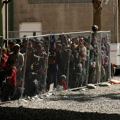 Dozens of people in an outdoor enclosure.