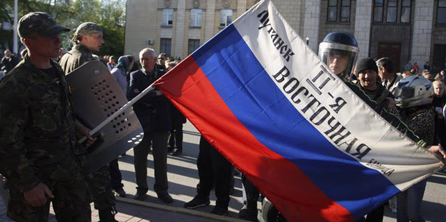 Milicianos prorrusos muestran una bandera rusa frente al edificio regional del Ministerio de Interior, en Lugansk.