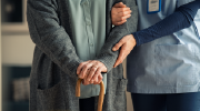 Close-up shot of a nurse assisting an older person with a walker.