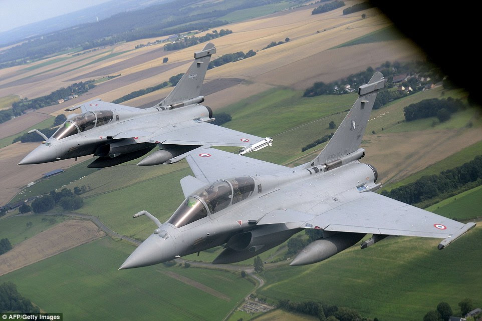 Two French Rafale fighter aircraft fly in tight formation on the wing of a Boeing C135 refueling tanker before approaching Paris for the flypast