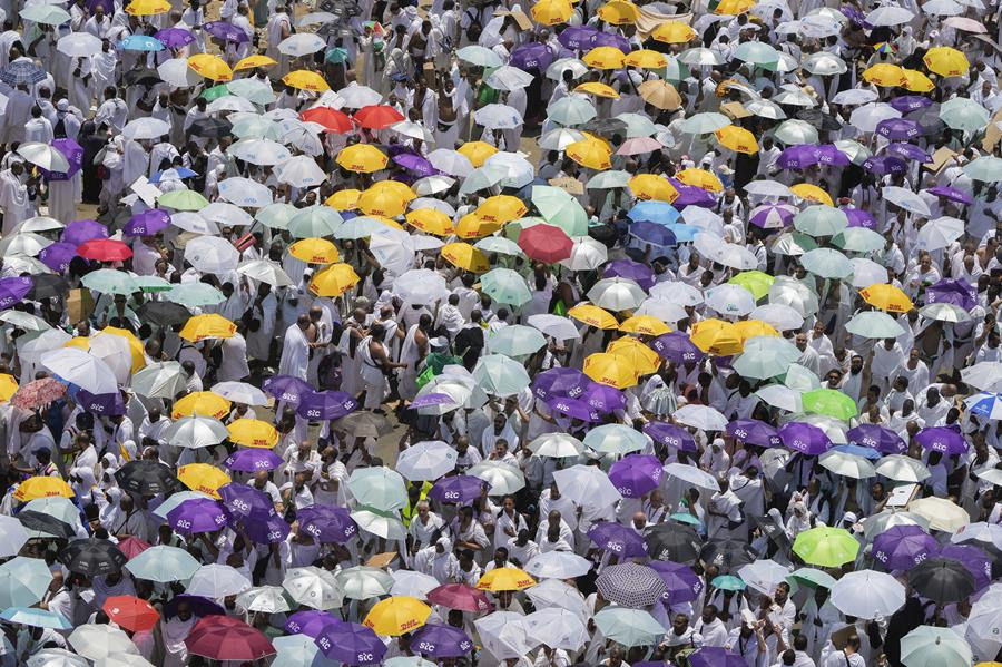 An overhead view of a crowd during the Hajj pilgrimage to Mecca. Many people in the crowd are carrying umbrellas.