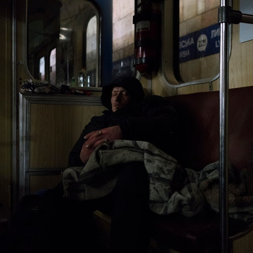 A man sleeps inside a car of a Kyiv subway station, used by people as a bomb shelter.