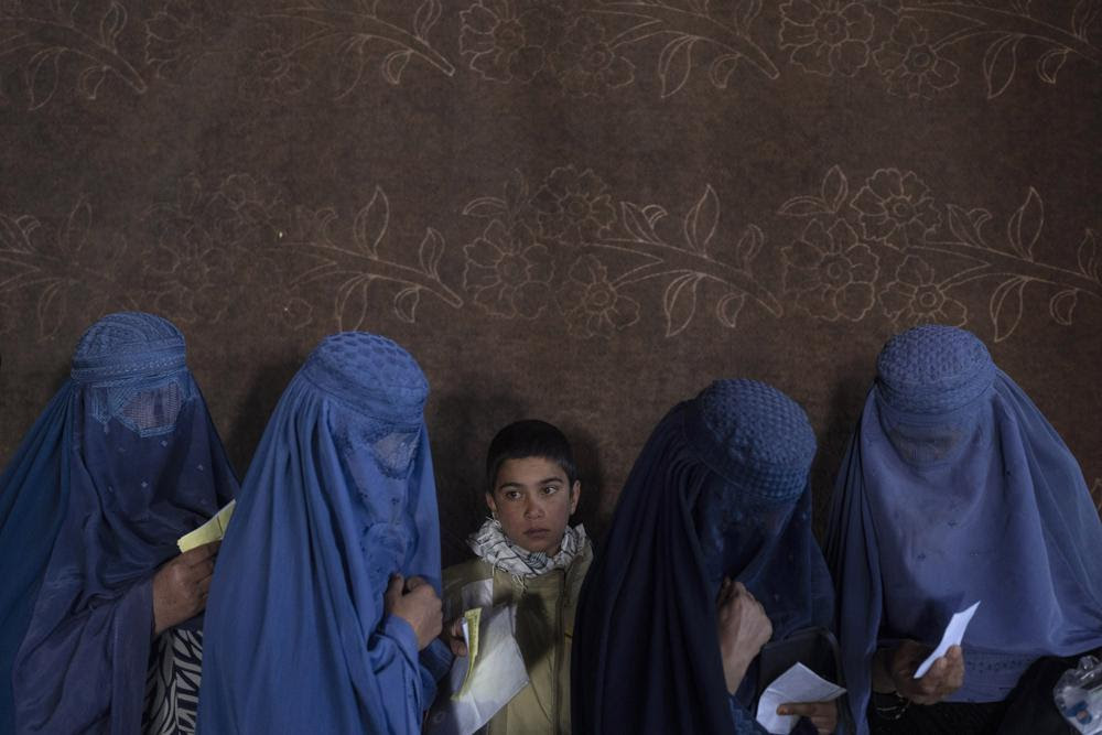 FILE - Afghan women wait to receive cash at a money distribution point organized by the World Food Program, in Kabul, Afghanistan, on Nov. 20, 2021. The lives of Afghan women and girls are being destroyed by the Taliban’s crackdown on their human rights, said Amnesty International in a new report Wednesday, July 27, 2022. The London-based watchdog criticized Taliban authorities saying that since Taliban took control of the country in August 2021, they have violated women’s and girls’ rights to education, work and free movement. (AP Photo/Petros Giannakouris, File)