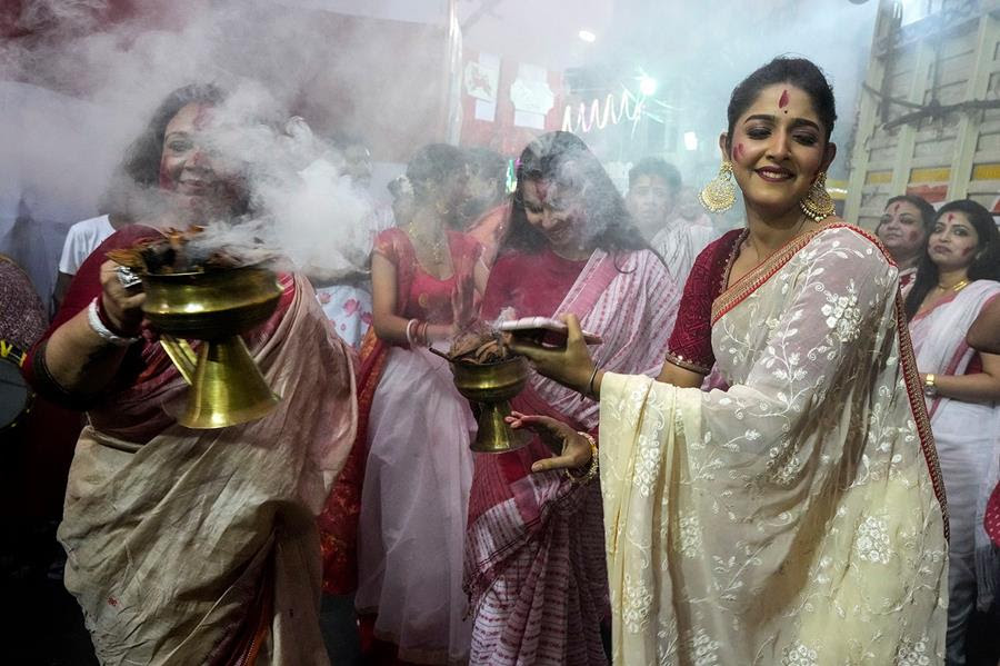 Women dance in front of an idol of Hindu goddess Durga.