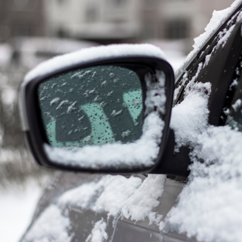 Driver side car mirror covered in snow