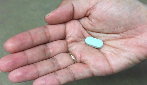 Woman's hand holding antiretroviral pill