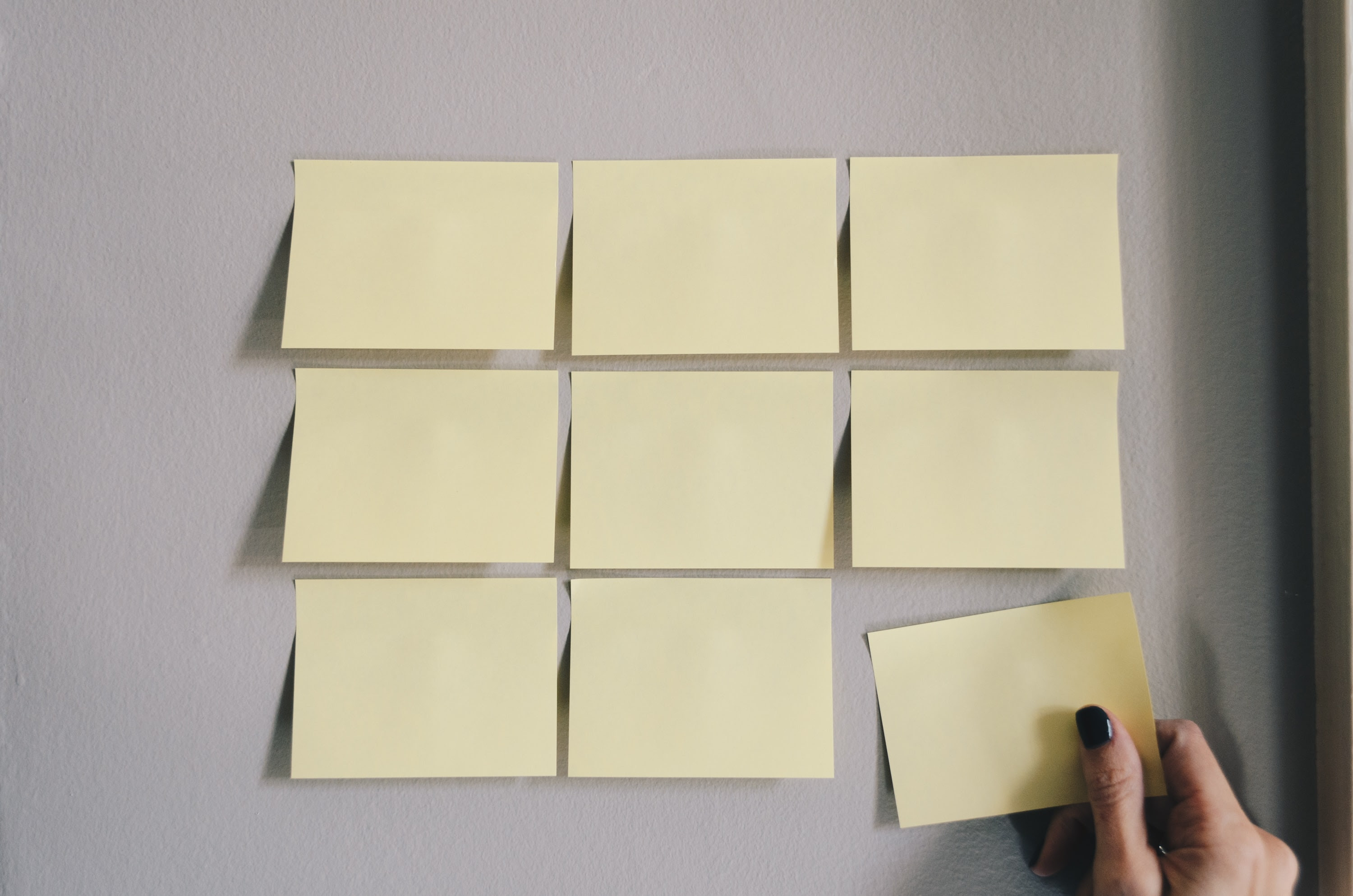 Photo of a series of yellow post it notes on a white wall.