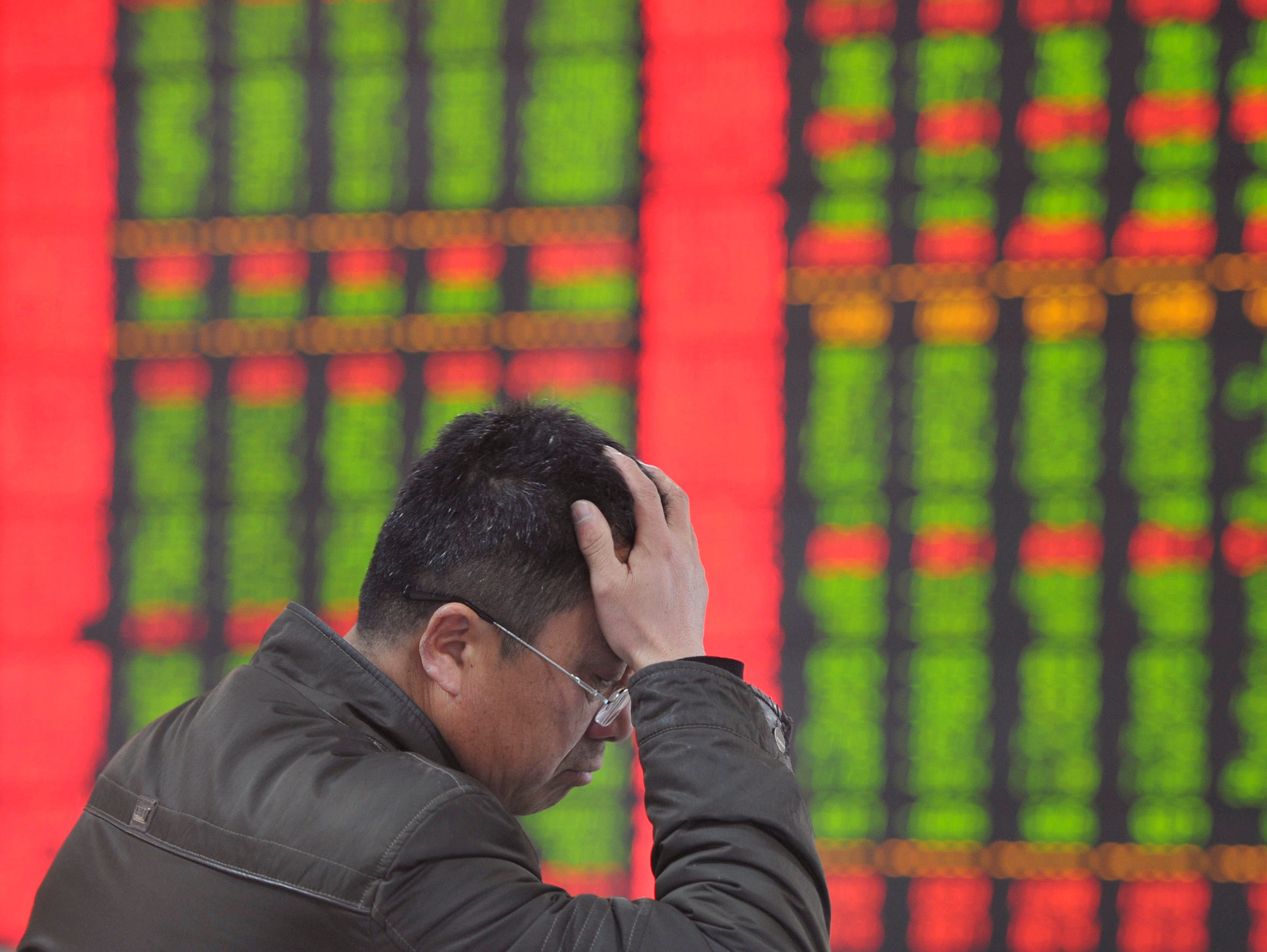 An investor holds his head as he monitors stock prices at a brokerage house in Fuyang in central China's Anhui province Monday, Jan. 19, 2015.