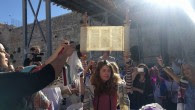 A young member of Women of the Wall holds up the miniature Torah scroll during the monthly Rosh Hodesh service on June 25, 2017, in the women's section of the Western Wall plaza. (Melanie Lidman/Times of Israel)