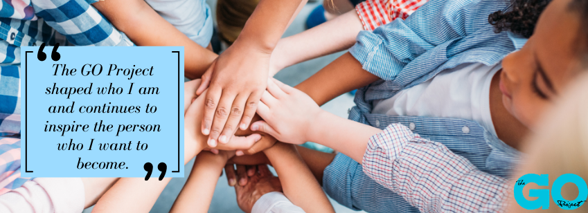 Bird's eye photo of children's hands, with a testimonial quote in a blue box that says "The GO Project shaped who I am and continues to inspire the person who I want to become."