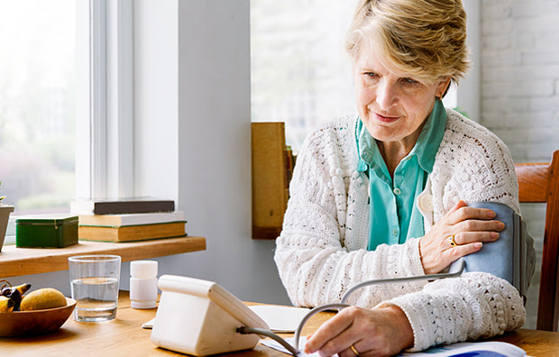 An elderly woman taking her blood pressure.