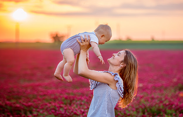 A mother holding her baby in the air.