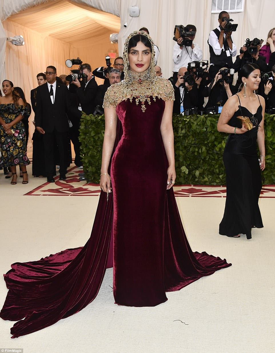 Ela tem esse fator: Priyanka Chopra escolheu um vestido de Borgonha e dourado com uma peÃ§a de cabeÃ§a;  o vestido Ã© Ralph Lauren