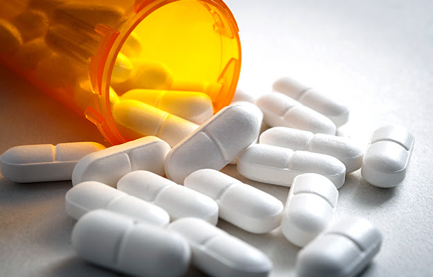 Opioid pills spilling out of a medicine bottle.