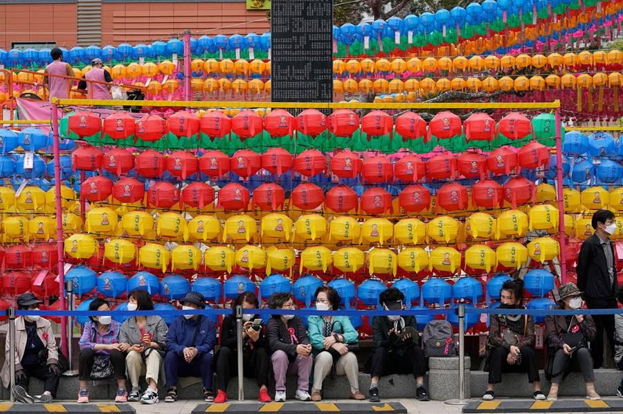 People sit in front of colorful rows of paper lanterns.