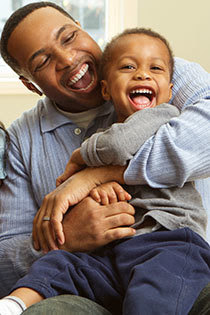 Smiling dad hugging laughing son